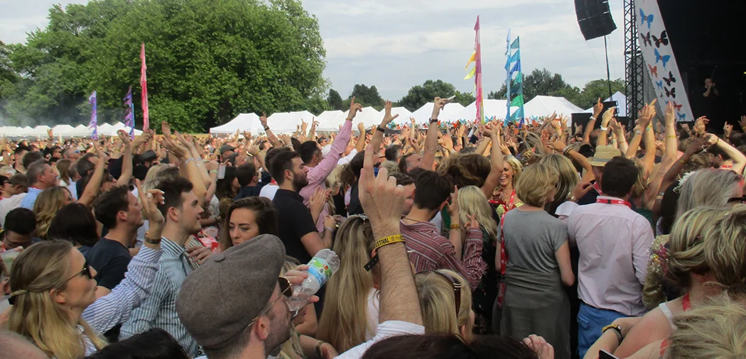 People at a festival with gazebos at the background